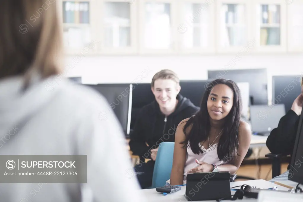 Smiling multi-ethnic students studying in computer lab at high school