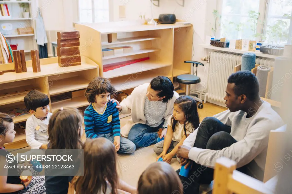 High angle view of teachers and students sitting in child care classroom