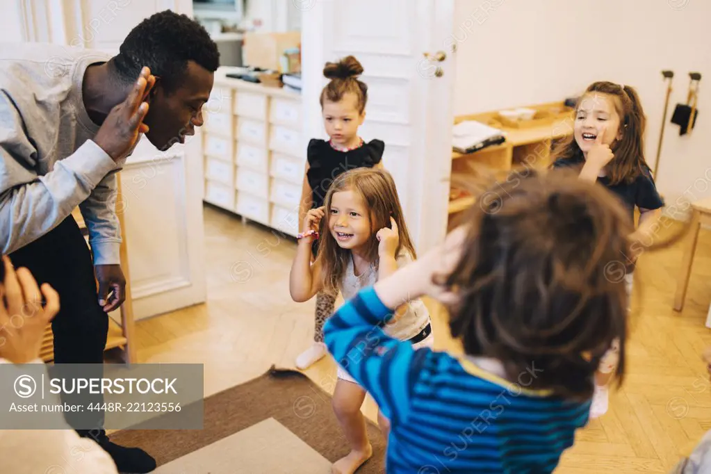 High angle view of teachers and students dancing in classroom at child care