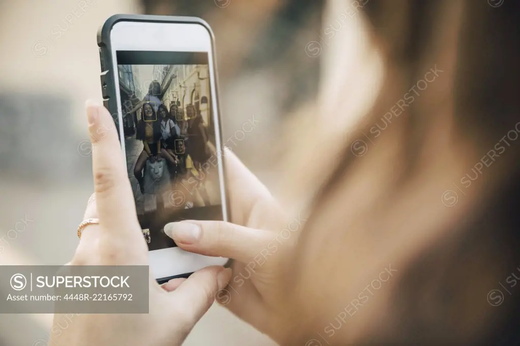 Smiling female friends posing in city seen on smart phone screen