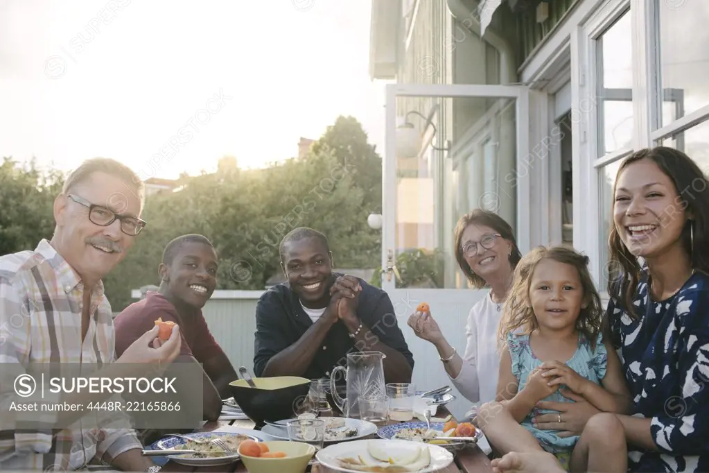 Portrait of smiling multi-generation family enjoying lunch at table on porch