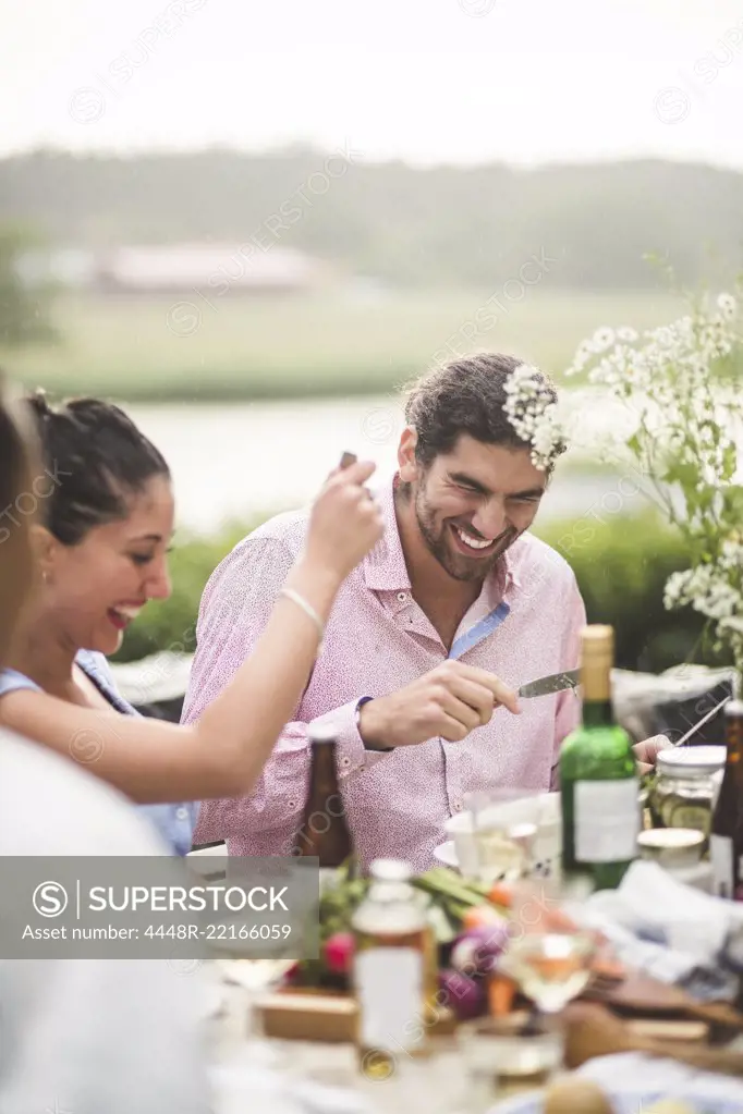 Cheerful male and female friends enjoying dinner party during in backyard