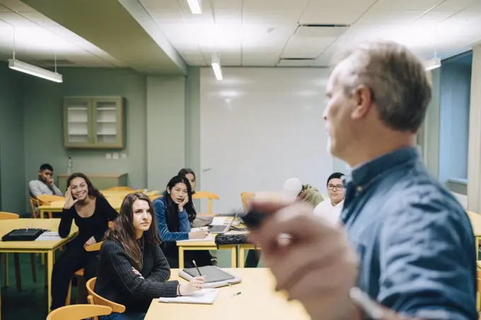 Male teacher teaching high school students in classroom