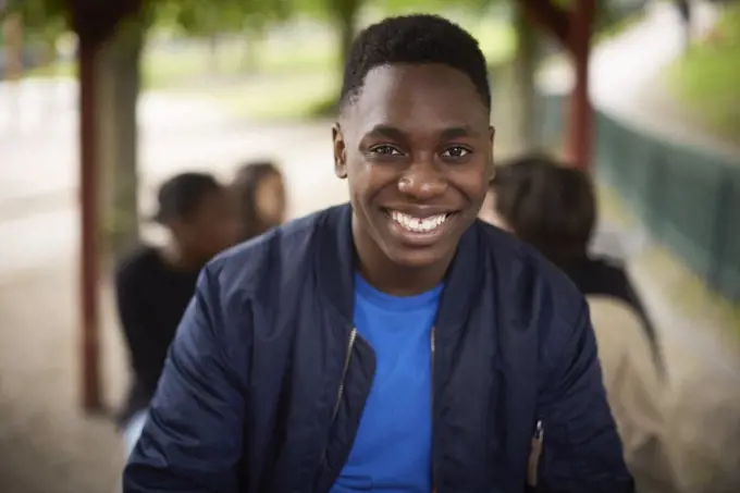 Portrait of smiling teenage boy sitting at park