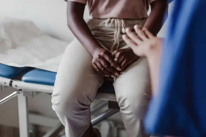 Midsection of female healthcare worker explaining to young patient in medical clinic