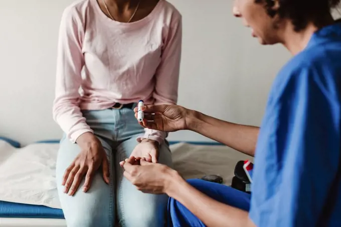 Nurse checking blood sugar of patient in medical examination room