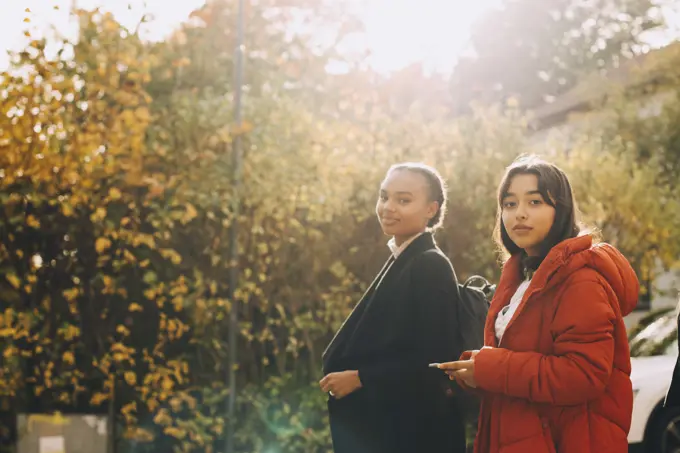 Portrait of teenage girls in jacket against trees during autumn