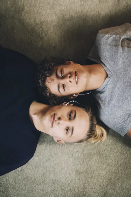 Directly above portrait of teenage boys lying together on carpet at home