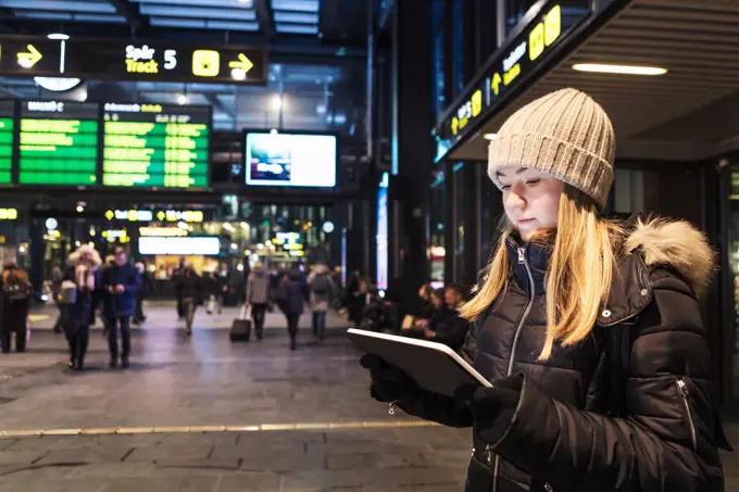 Teenage girl using digital tablet while standing in city during winter