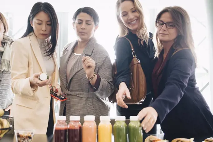 Multi-ethnic businesswomen looking at food and drink on table in event