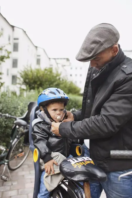 Man helsping son with helmet