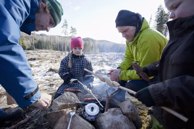 Men cooking while children looking at camping site