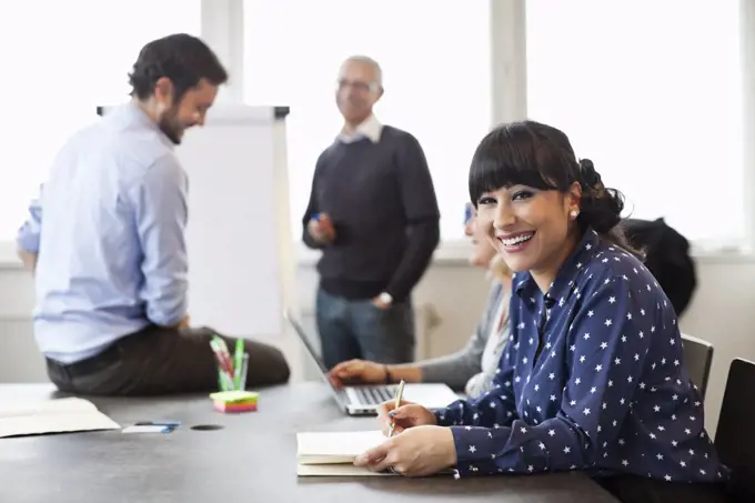 Smiling businesswoman with colleagues in background