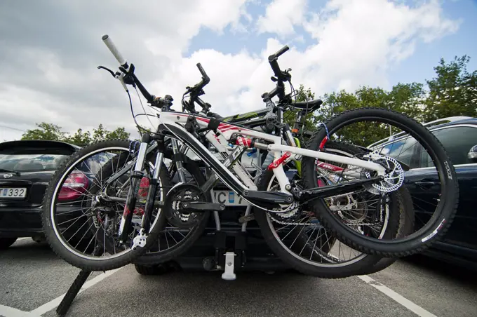 Bicycles locked to car at parking lot