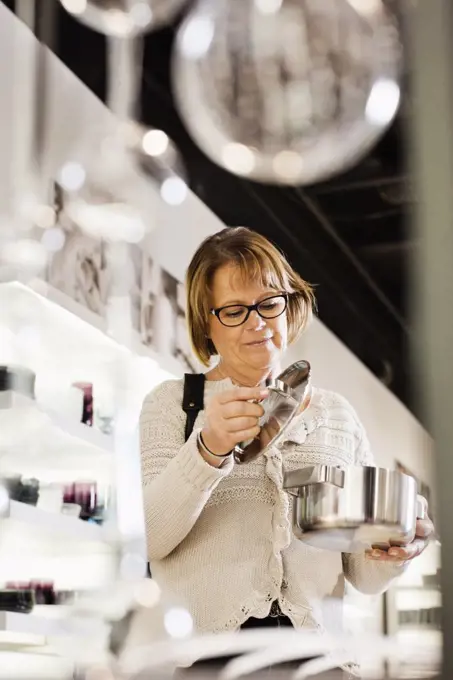 Senior woman buying cookware in shopping mall