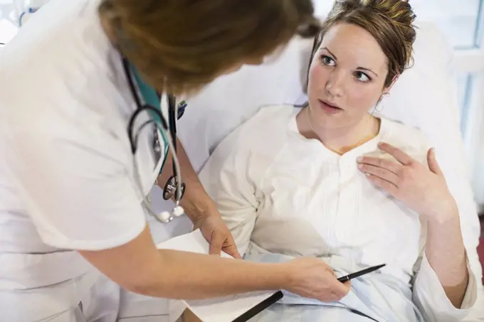 High angle view of female patient communicating with doctor in hospital ward