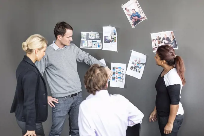 Business colleagues looking at photographs on wall in office