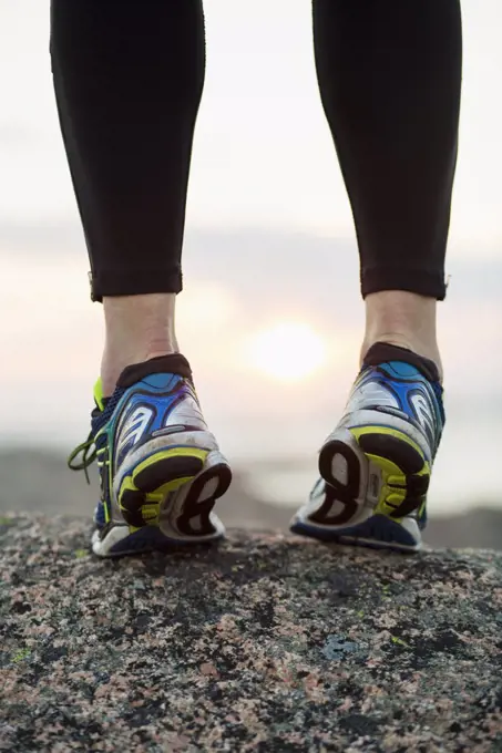 Low section of woman in sports shoes standing on toes outdoors