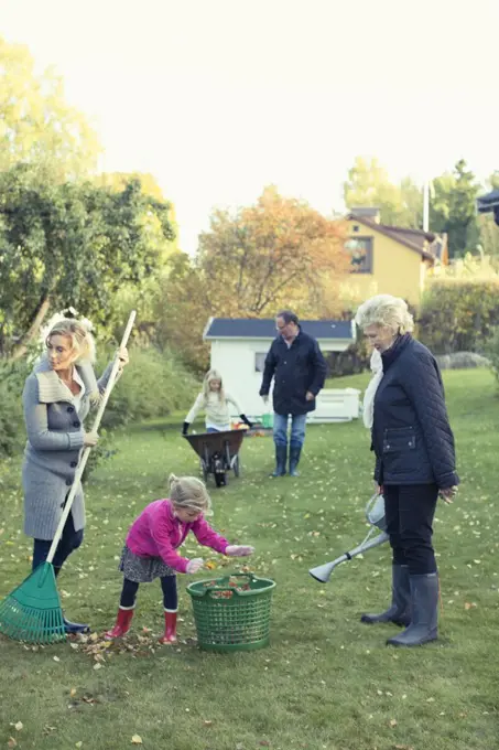 Family raking autumn leaves at yard