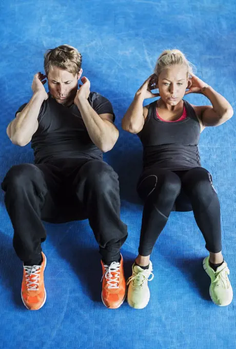 High angle view of friends doing sit-ups at gym