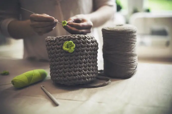 Midsection of woman knitting woolen purse at home