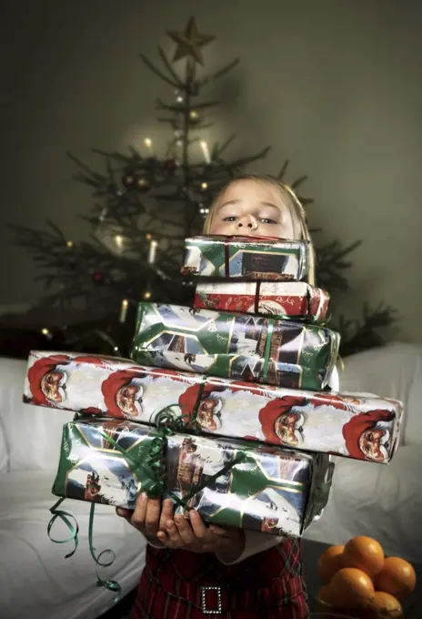 Girl behind pile of Christmas gifts