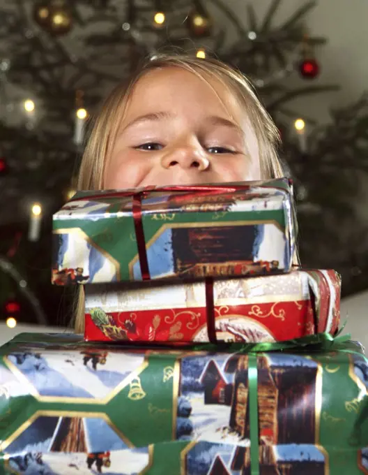 Girl looking out from pile of Christmas gifts