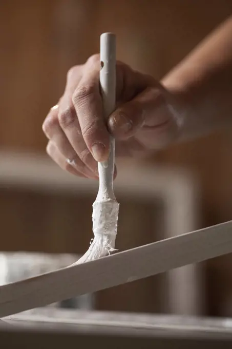 Cropped image of female upholsterer painting wooden plank