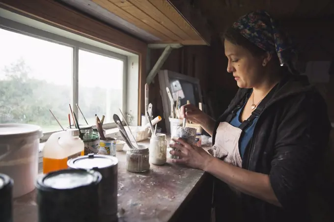 Side view of female upholsterer mixing paint at table