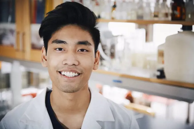 Portrait of confident young male university student standing at chemistry laboratory