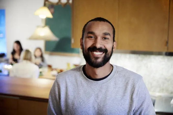 Portrait of smiling mid adult man standing in kitchen at home