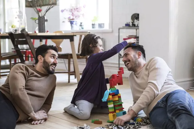 Cheerful fathers and daughter playing with toy blocks at home