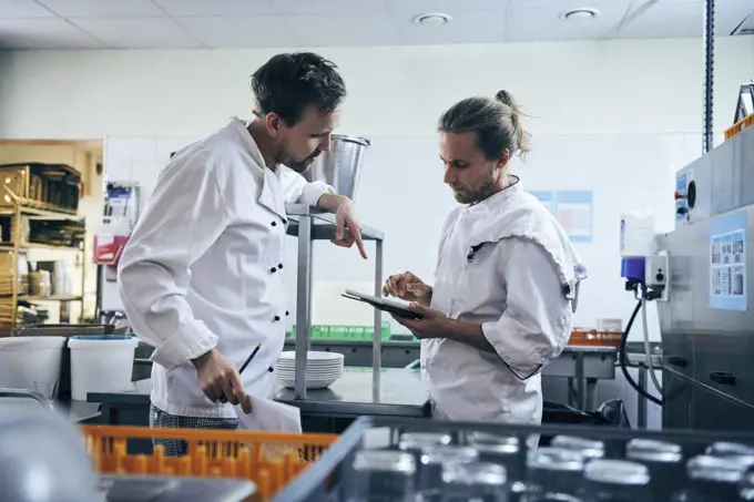 Chefs discussing over digital tablet in kitchen