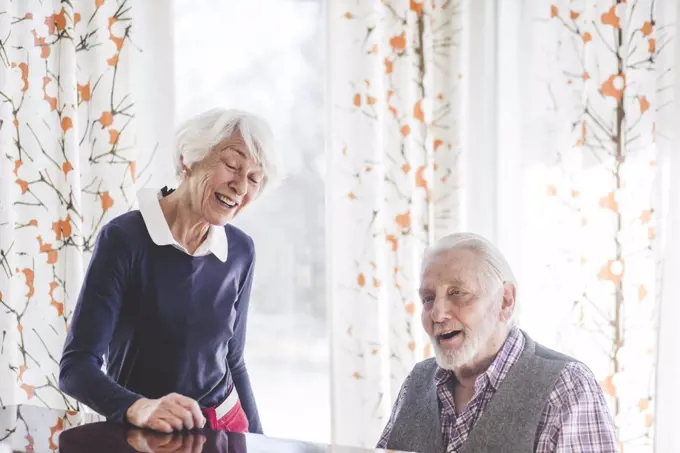 Senior man playing piano while woman singing in nursing home