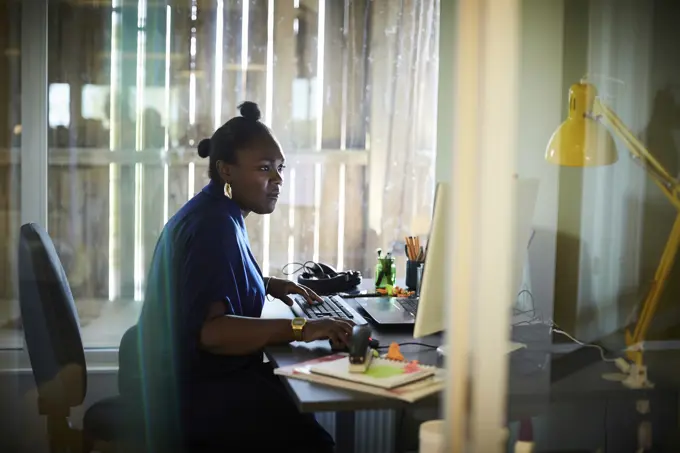 Side view of businesswoman working at computer desk in creative office