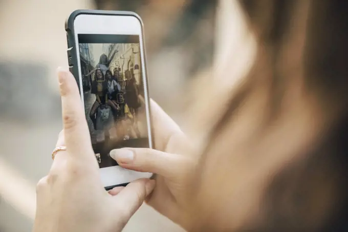 Smiling female friends posing in city seen on smart phone screen