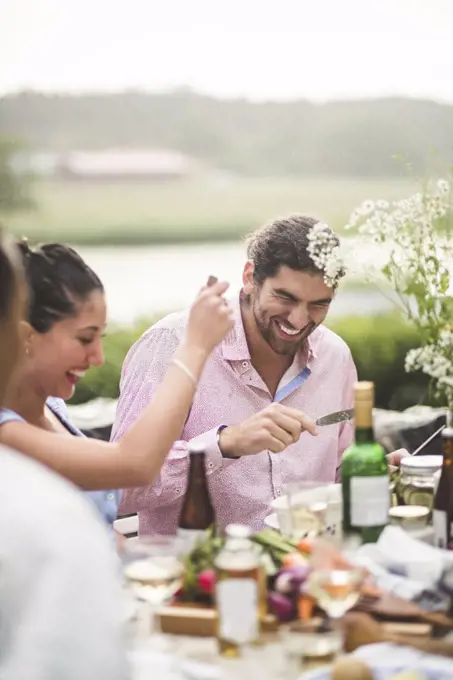 Cheerful male and female friends enjoying dinner party during in backyard