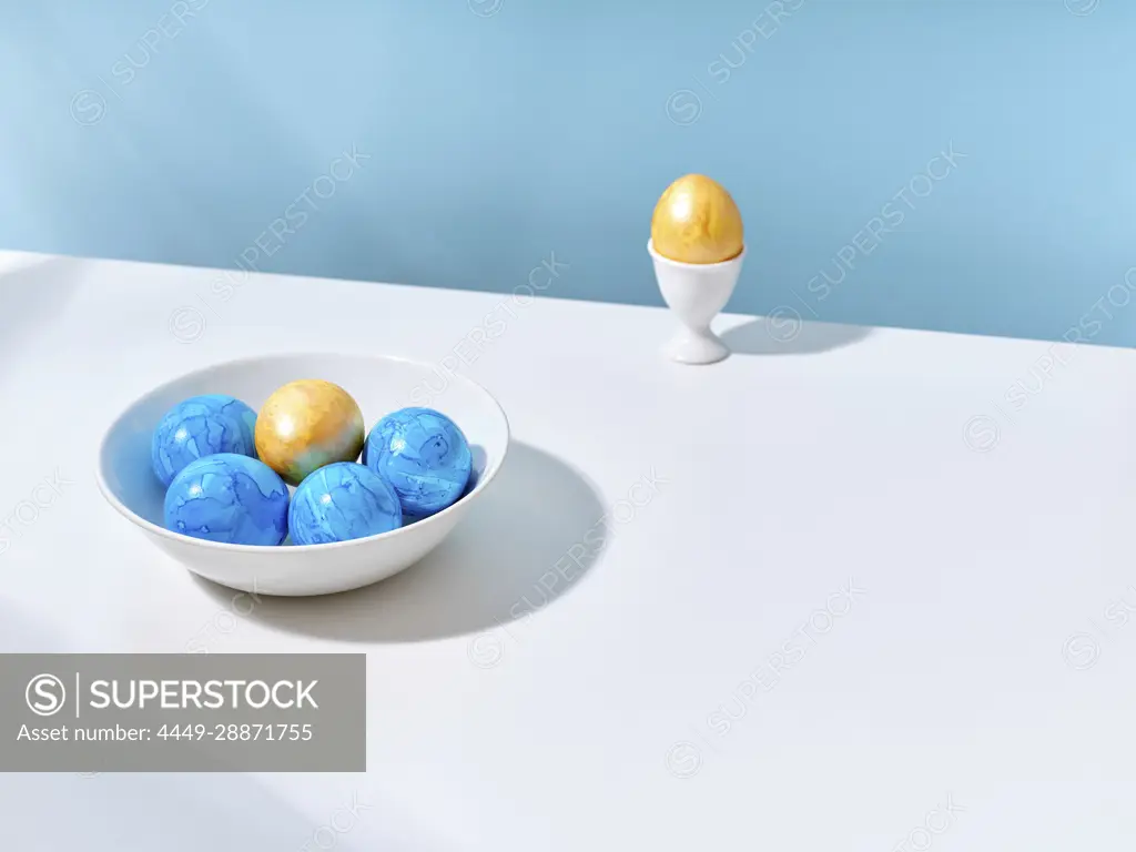 Creative layout with colored blue and golden easter eggs on bright background