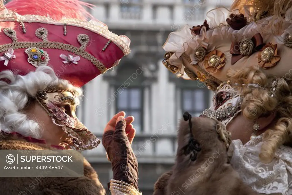 Two persons in the carnival costumes and wigs talking to each other, Venice, Italy