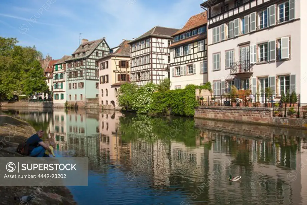 Father and daughter feeding ducks along canal with half timbered houses in La Petite France district, Strasbourg, Alsace, France, Europe