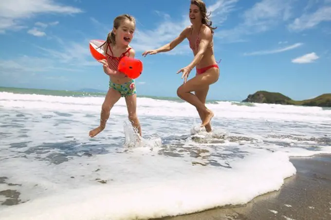 Children playing with their mother on the beach, Port Jackson on the northern tip of Coromandel Peninsula, North Island, New Zealand