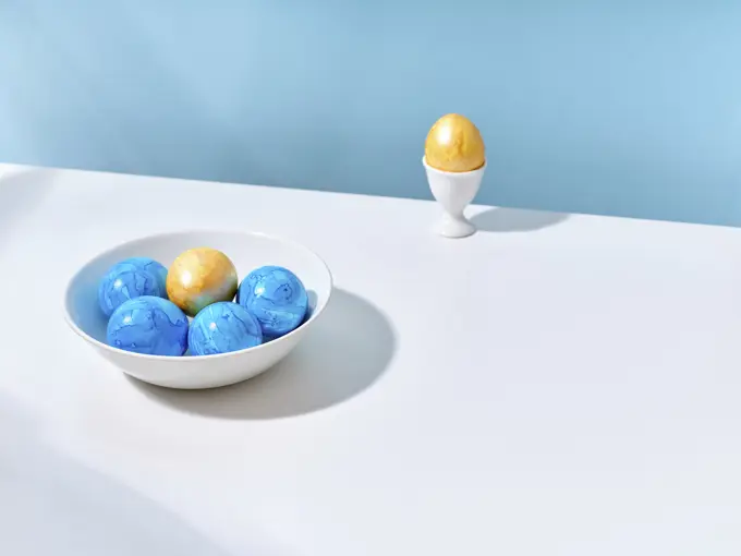 Creative layout with colored blue and golden easter eggs on bright background