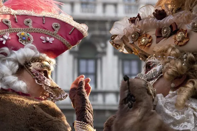 Two persons in the carnival costumes and wigs talking to each other, Venice, Italy