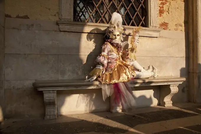 A woman in the carnival costume sitting on the bench, Venice, Italy