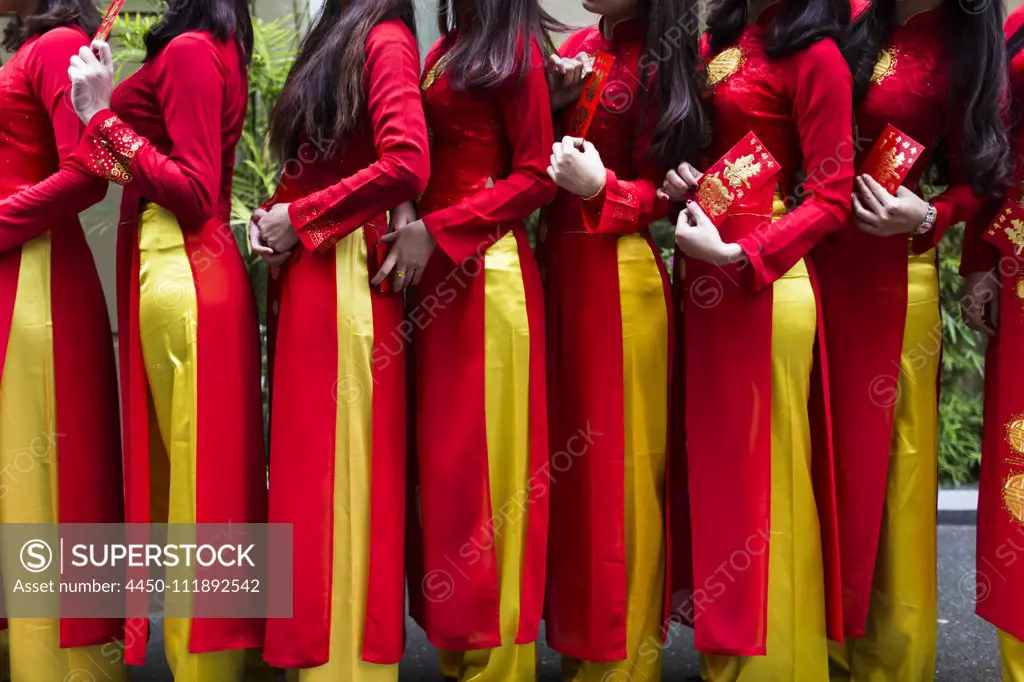 Close up of line of young women in traditional red and yellow dress outside of a wedding.