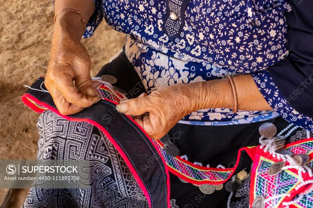 Woman seated stitching, making traditional garments, Vang Vieng, Laos