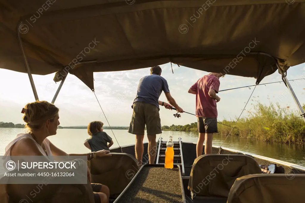 A group of tourists, family fishing from a boat on the Zambezi River, Botswana