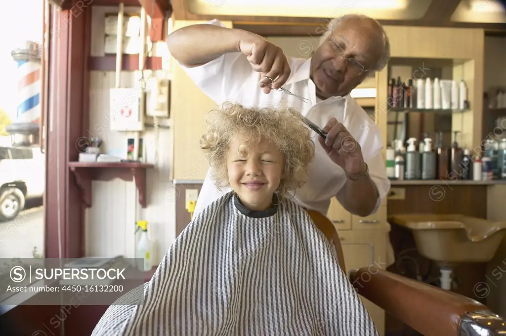 Young boy crying while barber cuts his hair