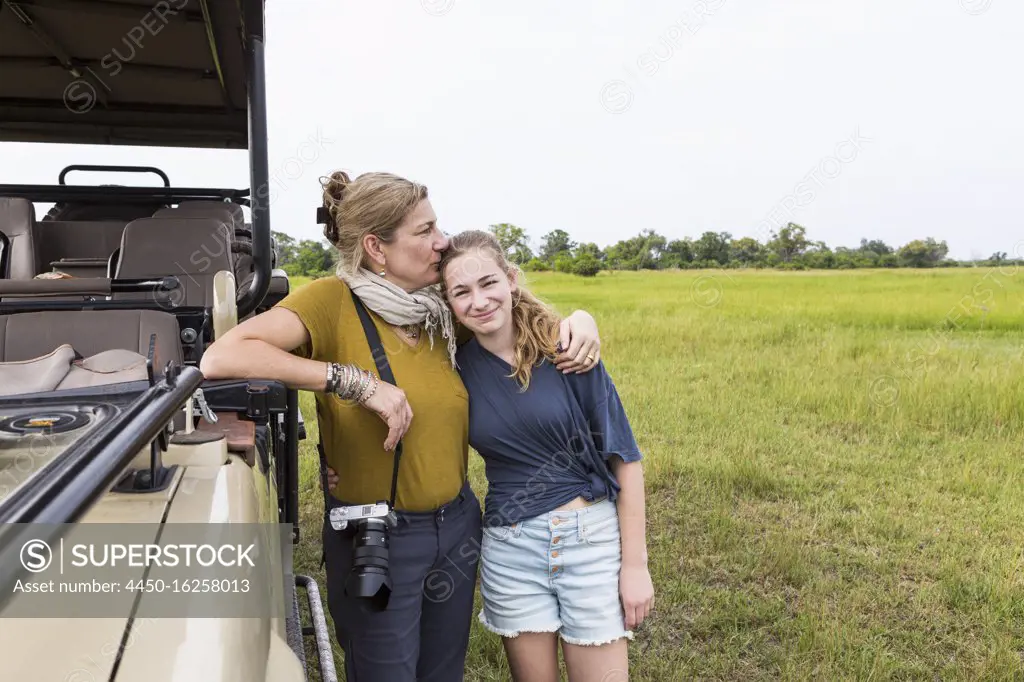 mother photographing with teen daughter near safari vehicle, Botswana