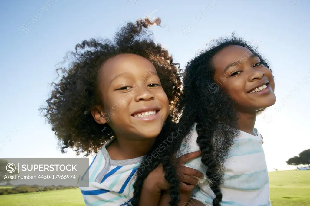 Young mixed race girl giving her younger brother a piggyback lift